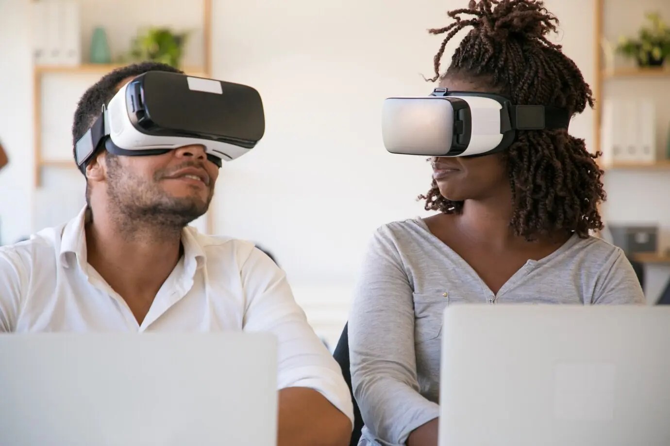 Probadores afroamericanos emocionados que llevan gafas de realidad virtual en una oficina.